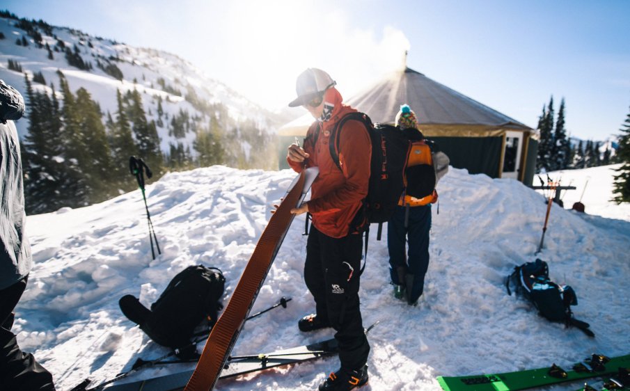 Skier putting on climbing skins outside yurt
